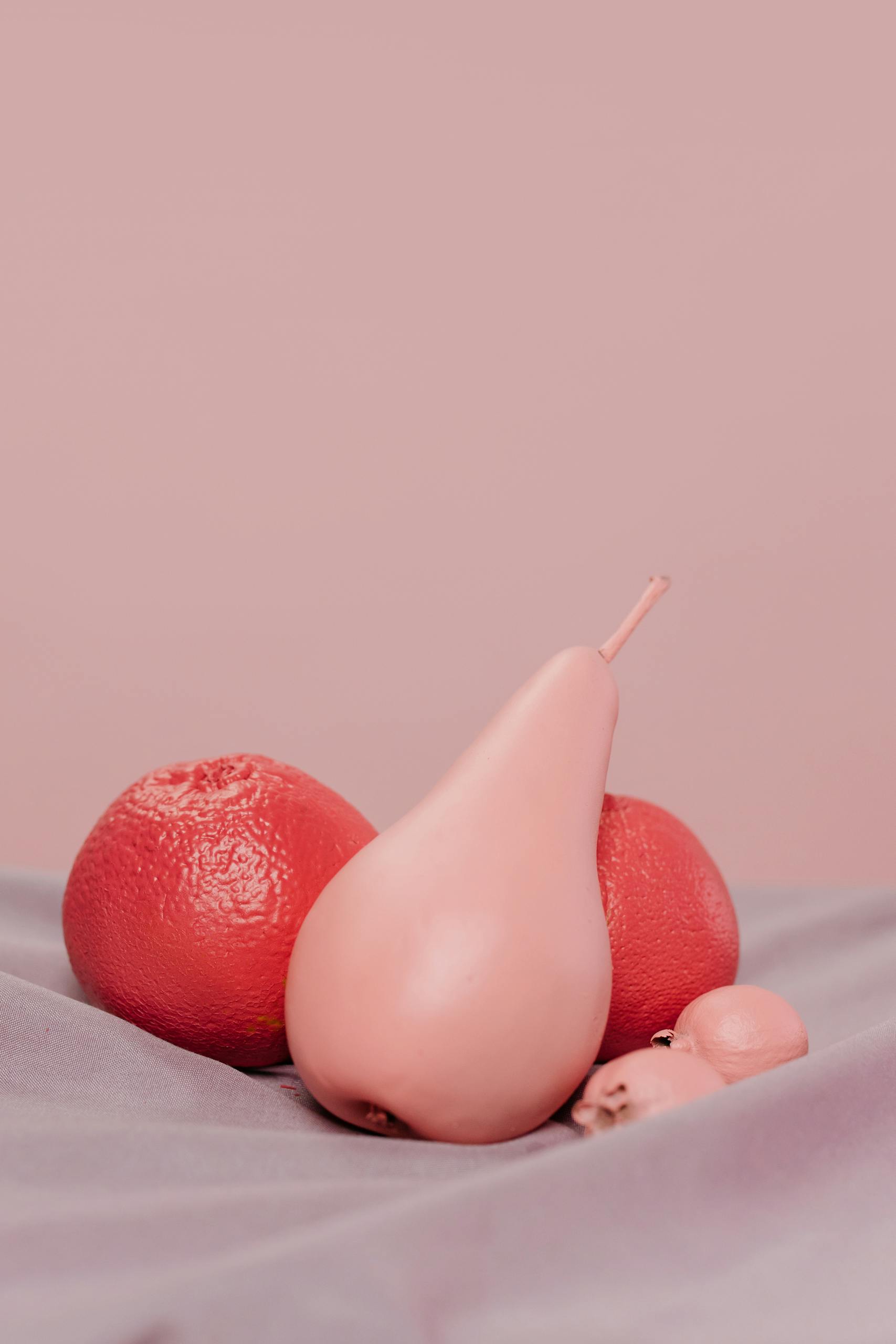 Grapefruits and a Pear on a Pink Background