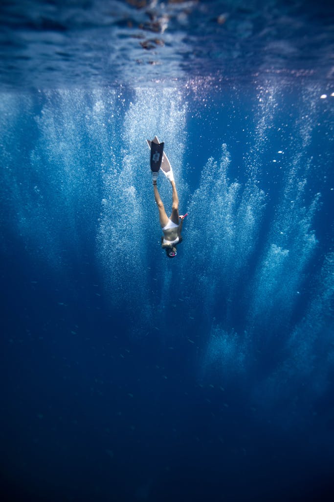 Unrecognizable lady swimming underwater after jumping in ocean